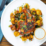 Overhead easy roast chicken legs served with onion and Bombay roast potatoes.