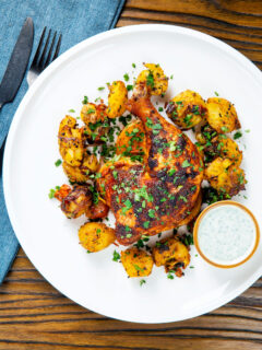 Overhead easy roast chicken legs served with onion and Bombay roast potatoes.