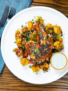 Overhead easy roast chicken legs served with onion and Bombay roast potatoes.