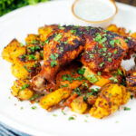 Easy roast chicken legs served with onion and Bombay roast potatoes.