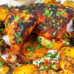 Indian spiced roast chicken legs served with onion, Bombay potatoes and raita.