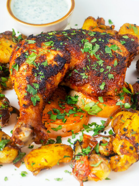 Indian spiced roast chicken legs served with onion, Bombay potatoes and raita.