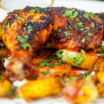 Close-up Indian spiced roast chicken legs served with onion, Bombay potatoes and raita.