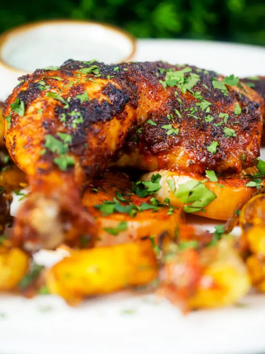 Close-up Indian spiced roast chicken legs served with onion, Bombay potatoes and raita.