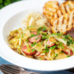 Polish noodles or lazanki with kielbasa sausage and cabbage served with bread and sauerkraut.