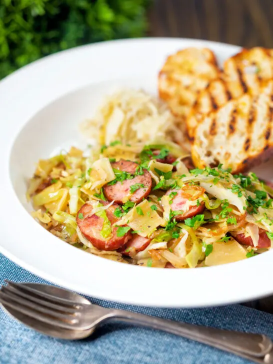 Polish noodles or lazanki with kielbasa sausage and cabbage served with bread and sauerkraut.