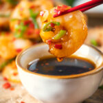 Close-up Chinese salt and pepper prawn dipped into a chilli dipping sauce.