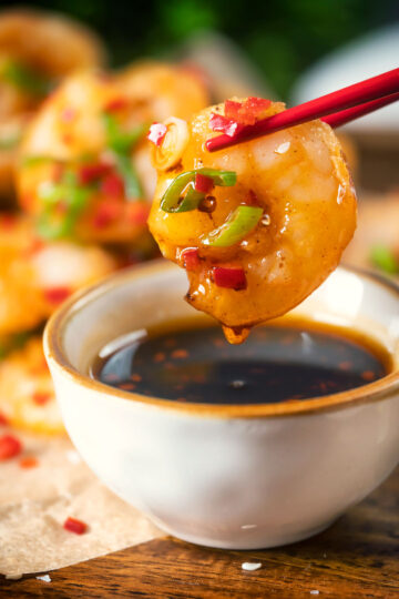 Close-up Chinese salt and pepper prawn dipped into a chilli dipping sauce.