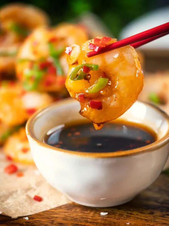 Close-up Chinese salt and pepper prawn dipped into a chilli dipping sauce.