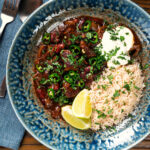 Overhead chunky beef chilli con carne cooked in a slow cooker served with brown rice.