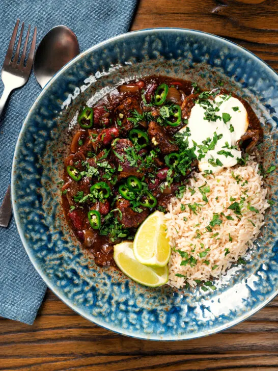 Overhead chunky beef chilli con carne cooked in a slow cooker served with brown rice.