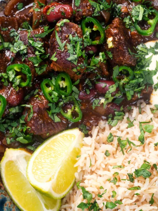 Overhead close-up chunky beef chilli con carne cooked in a slow cooker served with brown rice.
