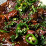Close-up chunky beef chilli con carne cooked in a slow cooker served with brown rice.