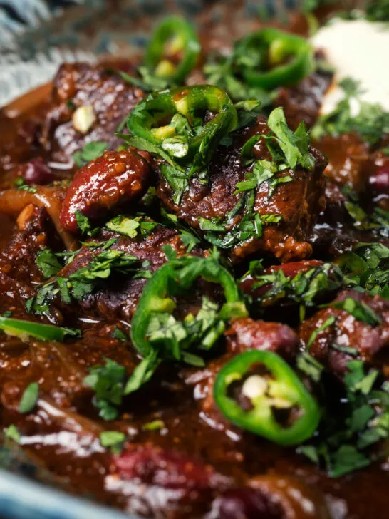 Close-up chunky beef chilli con carne cooked in a slow cooker served with brown rice.