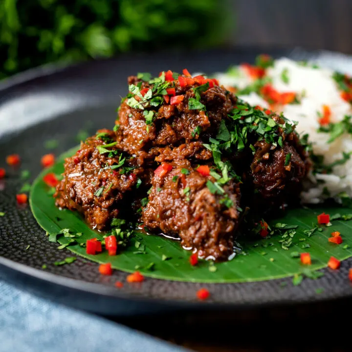 Malaysian influenced beef rendang curry served with rice on a banana leaf.