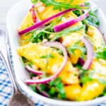 Spicy mango salad with chilli, red onion, rocket (arugula), lime and pine nuts.