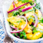 Spicy mango salad with chilli, red onion, rocket (arugula), lime and pine nuts featuring a title overlay.