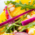 Close-up spicy mango salad with chilli, red onion, rocket (arugula), lime and pine nuts.