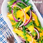 Overhead spicy mango salad with chilli, red onion, rocket (arugula), lime and pine nuts featuring a title overlay.