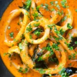 Close-up overhead Indian-influenced calamari ring curry in a spicy coconut sauce.