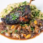 Tamarind and honey glazed duck leg with stewed onions, dates, almonds and buttered couscous.