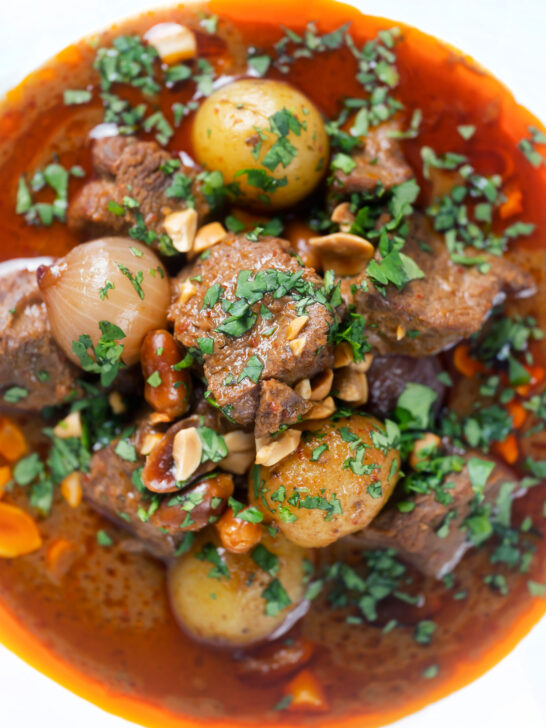 Overhead close-up spicy Thai beef massaman curry with potatoes, shallots and peanuts.