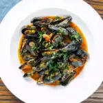 Overhead Thai inspired red curry mussels in a coconut milk sauce.