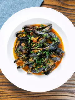 Overhead Thai inspired red curry mussels in a coconut milk sauce.