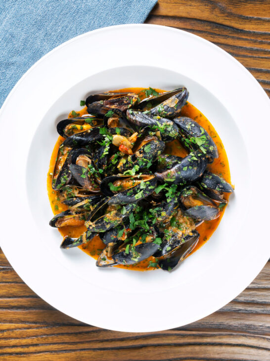 Overhead Thai inspired red curry mussels in a coconut milk sauce.