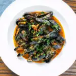 Overhead Thai inspired red curry mussels in a coconut milk sauce featuring a title overlay.