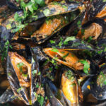 Overhead close-up Thai inspired red curry mussels in a coconut milk sauce.
