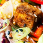 Close-up crispy soy sauce tofu and rice vermicelli noodle salad with lots of veggies.