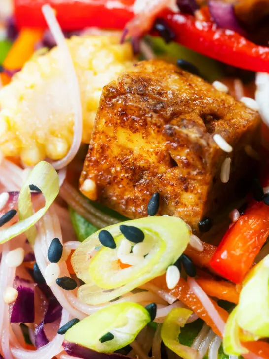 Close-up crispy soy sauce tofu and rice vermicelli noodle salad with lots of veggies.