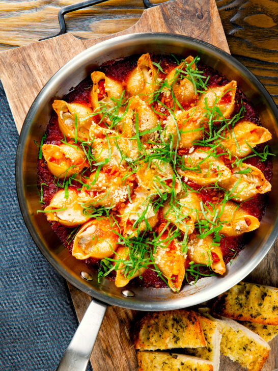 Overhead skillet baked stuffed pasta shells with goat's cheese and nduja in a tomato sauce.