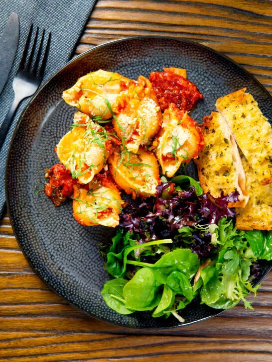 Baked stuffed pasta shells with goat's cheese and nduja in a tomato sauce with garlic bread.