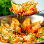 Stuffed pasta shells with goat's cheese and nduja in a tomato sauce being served.