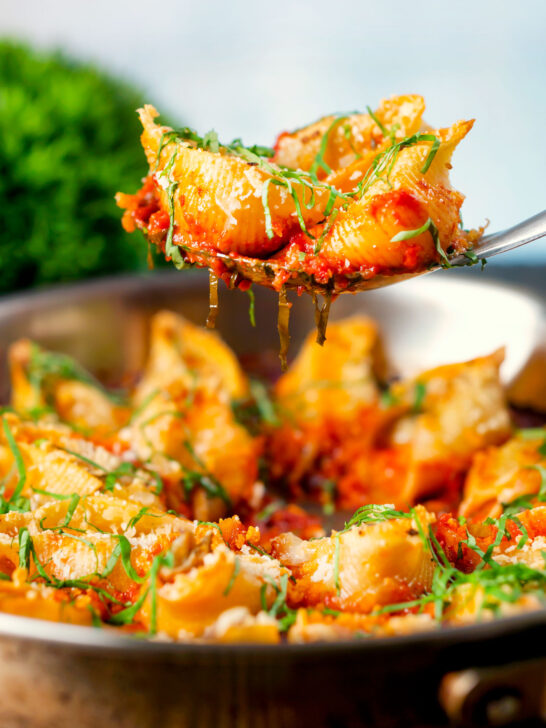 Stuffed pasta shells with goat's cheese and nduja in a tomato sauce being served.