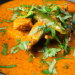 Close-up Indian coconut milk chicken curry with tamarind and fresh coriander.