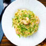 Overhead prawn pesto pasta with linguine and fresh basil.