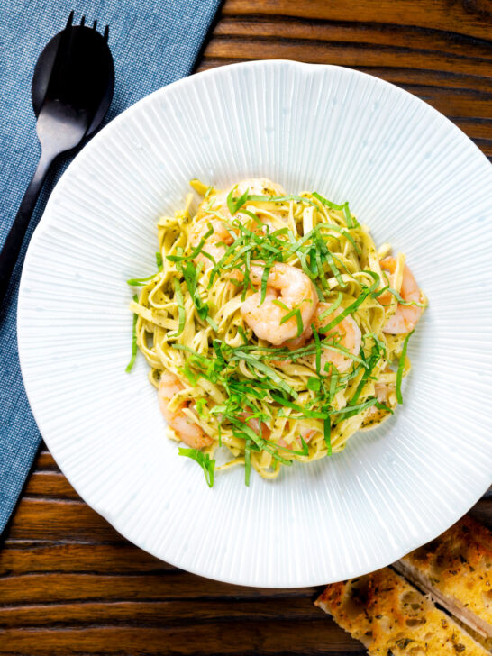 Overhead prawn pesto linguine with linguine and fresh basil.