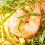Close-up prawn pesto linguine with fresh basil chiffonade.
