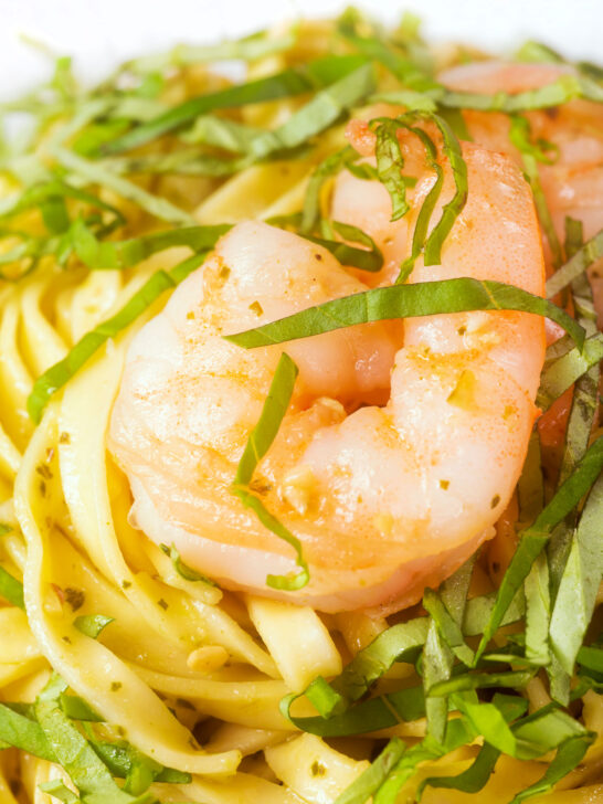 Close-up prawn pesto linguine with fresh basil chiffonade.