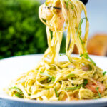 Prawn pesto pasta with basil pesto, jumbo shrimp and linguine being picked up with a fork.