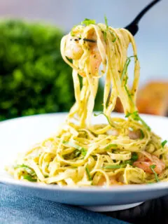 Prawn pesto pasta with basil pesto, jumbo shrimp and linguine being picked up with a fork.