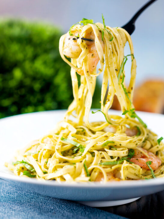 Prawn pesto pasta with basil pesto, jumbo shrimp and linguine being picked up with a fork.