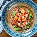 Overhead grilled and marinated halloumi salad with peppers, couscous and chickpeas featuring a title overlay.