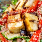 Close-up grilled and marinated halloumi salad with peppers, couscous and chickpeas.