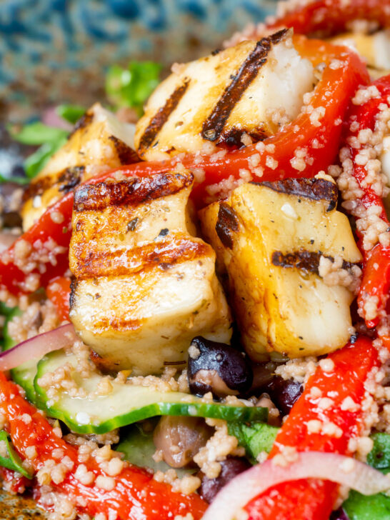 Close-up grilled and marinated halloumi salad with peppers, couscous and chickpeas.