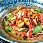 Close-up grilled and marinated halloumi salad with peppers, couscous and chickpeas.
