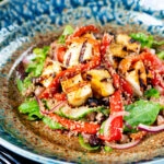 Close-up grilled and marinated halloumi salad with peppers, couscous and chickpeas.